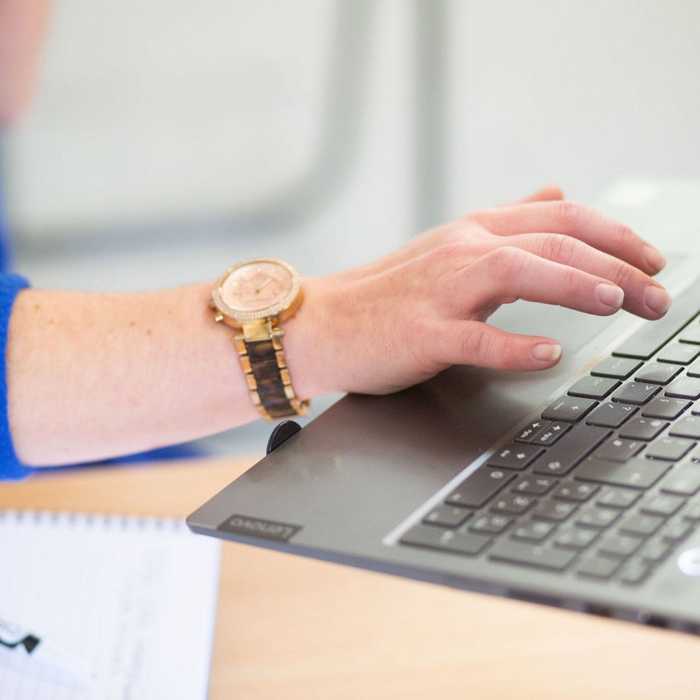 Person wearing a watch typing on a laptop keyboard