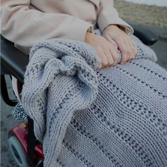 Elderly person on a disability scooter with a blanket