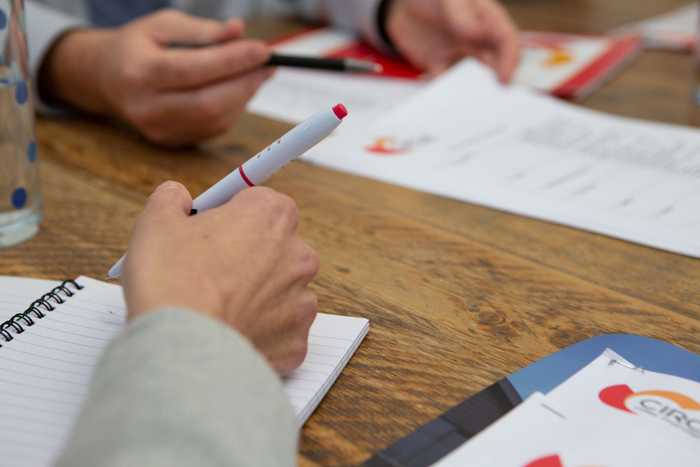 Close up of people's hands and notebooks on a table, conducting mental capacity assessments